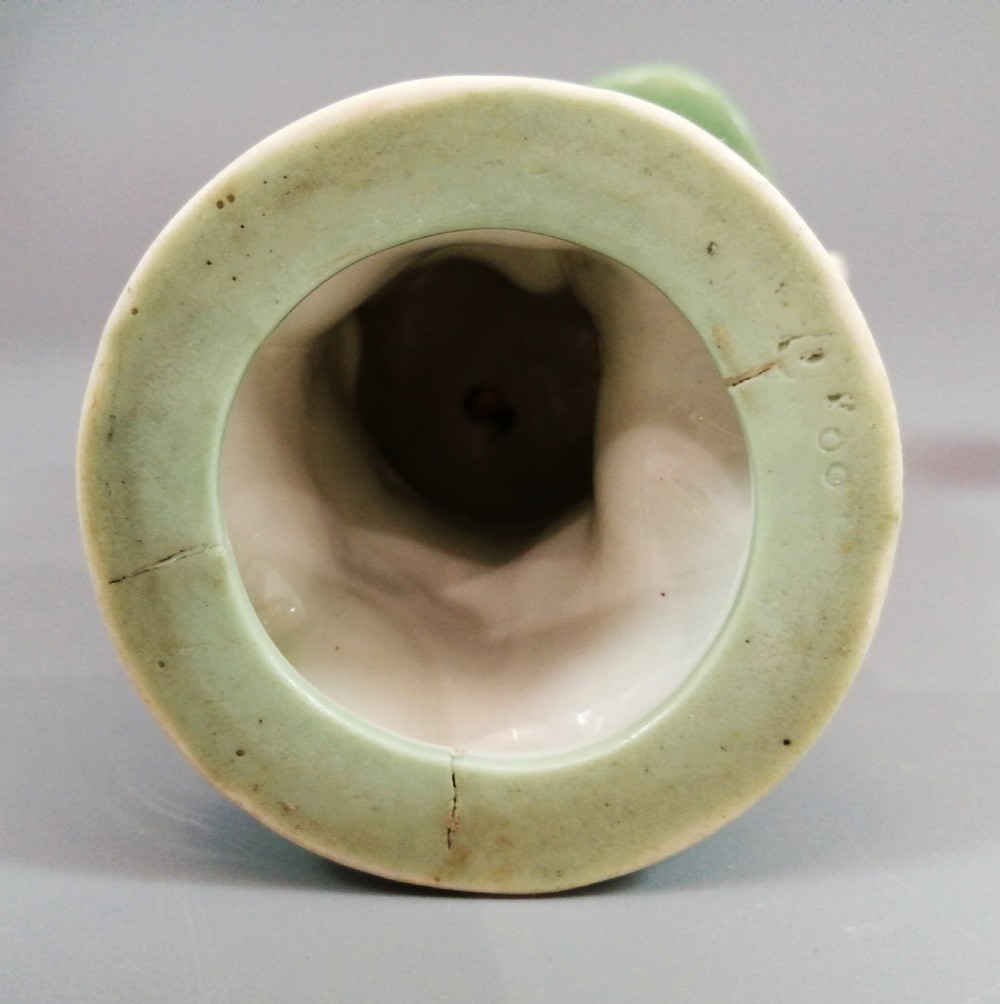 A pair of Victorian Minton celadon green and white porcelain figurines depicting a seated man and woman holding oval dishes on circular bases. View VIII