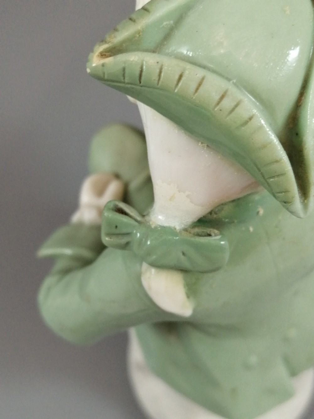A pair of Victorian Minton celadon green and white porcelain figurines depicting a seated man and woman holding oval dishes on circular bases. View XI