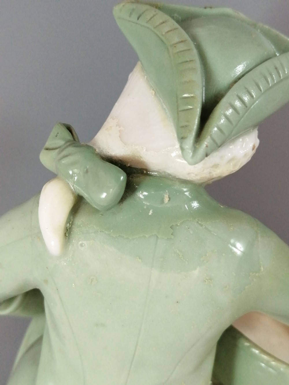 A pair of Victorian Minton celadon green and white porcelain figurines depicting a seated man and woman holding oval dishes on circular bases. View XII