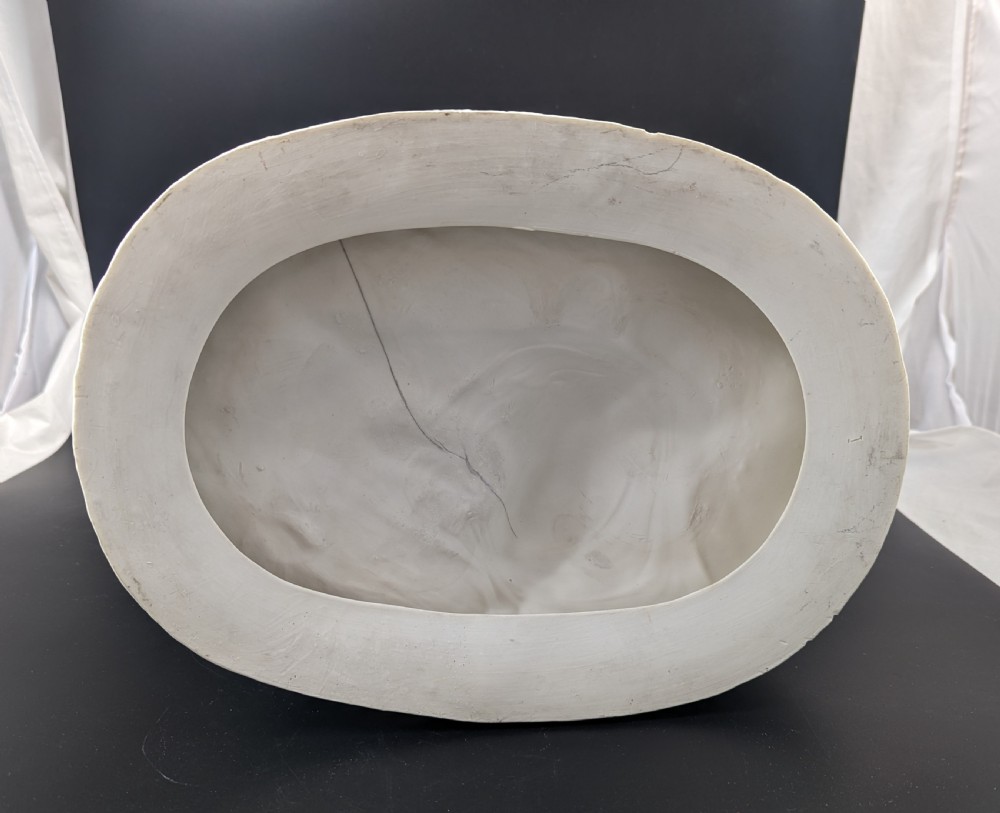 An off-white Parian porcelain sculpture depicting Rebekah offering water from an amphora to a kneeling man beside a textured stone well. View XIV