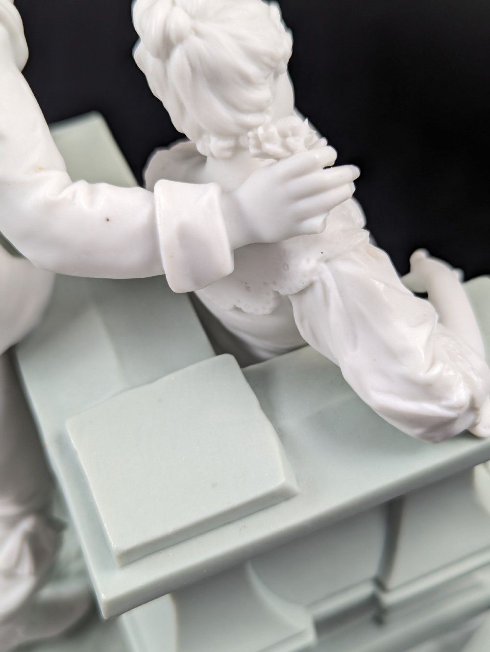 A white and pale green parian porcelain figurine depicting a courtly man and woman interacting beside a balustrade. View XI