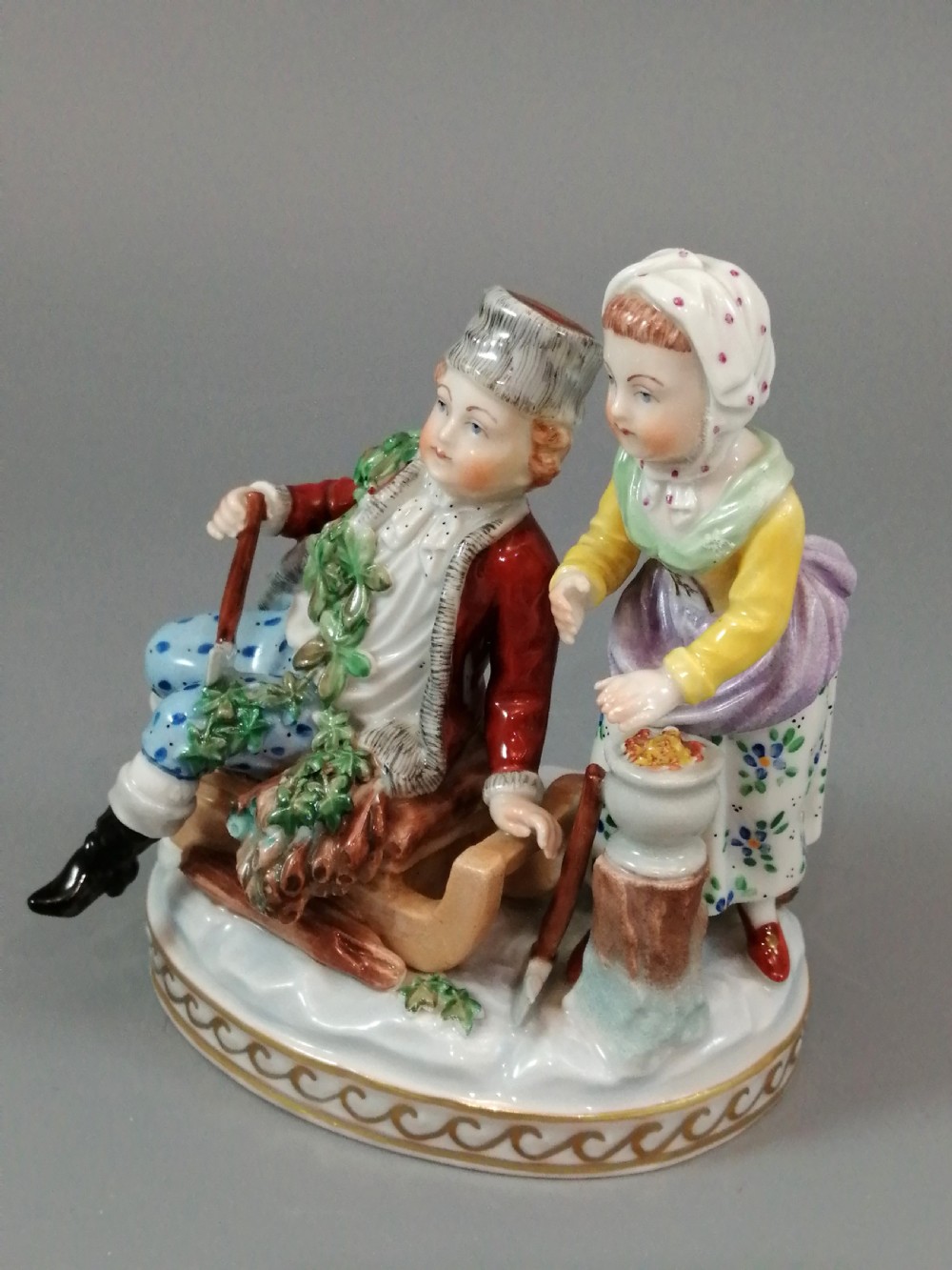 A Carl Thieme Potschappel hand-painted porcelain figurine depicting a young couple in eighteenth-century winter costume beside a sledge and brazier. View II