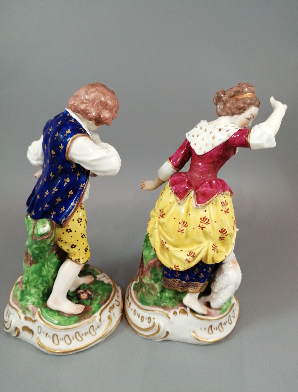 A pair of 19th-century French Samson porcelain figurines depicting a young boy with a basket of fruit and a dog alongside a shepherdess with a lamb, decorated with polychrome enamels and gilded scroll bases. View IV