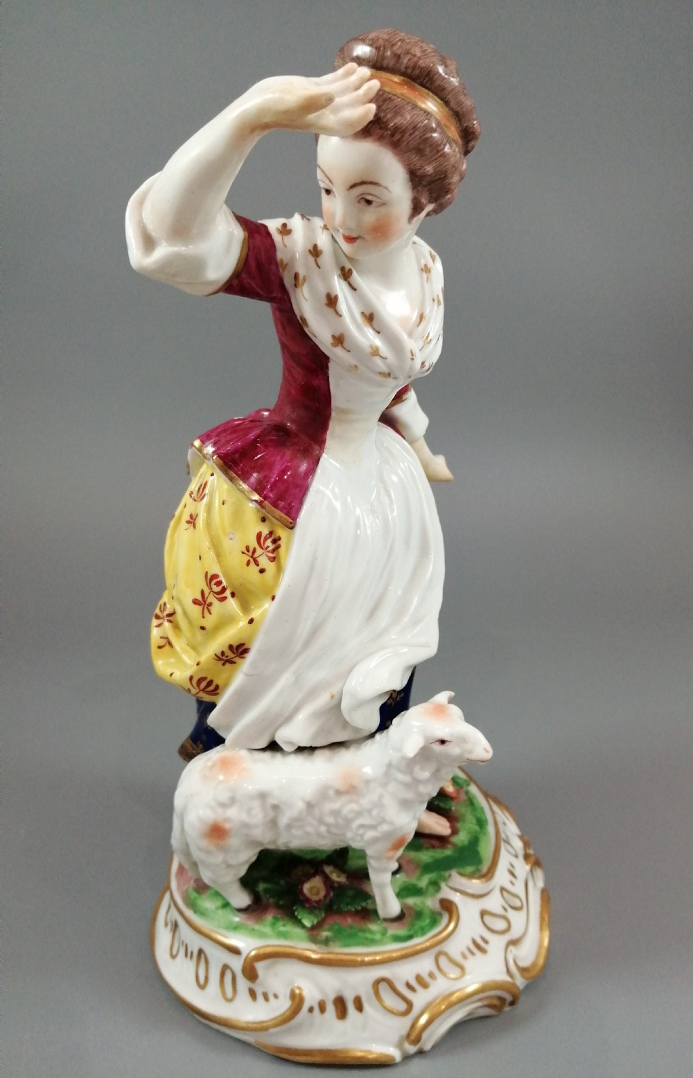 A pair of 19th-century French Samson porcelain figurines depicting a young boy with a basket of fruit and a dog alongside a shepherdess with a lamb, decorated with polychrome enamels and gilded scroll bases. View VII