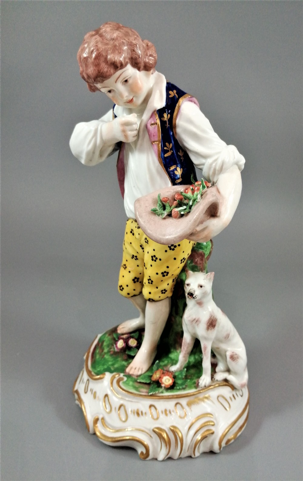 A pair of 19th-century French Samson porcelain figurines depicting a young boy with a basket of fruit and a dog alongside a shepherdess with a lamb, decorated with polychrome enamels and gilded scroll bases. View XI