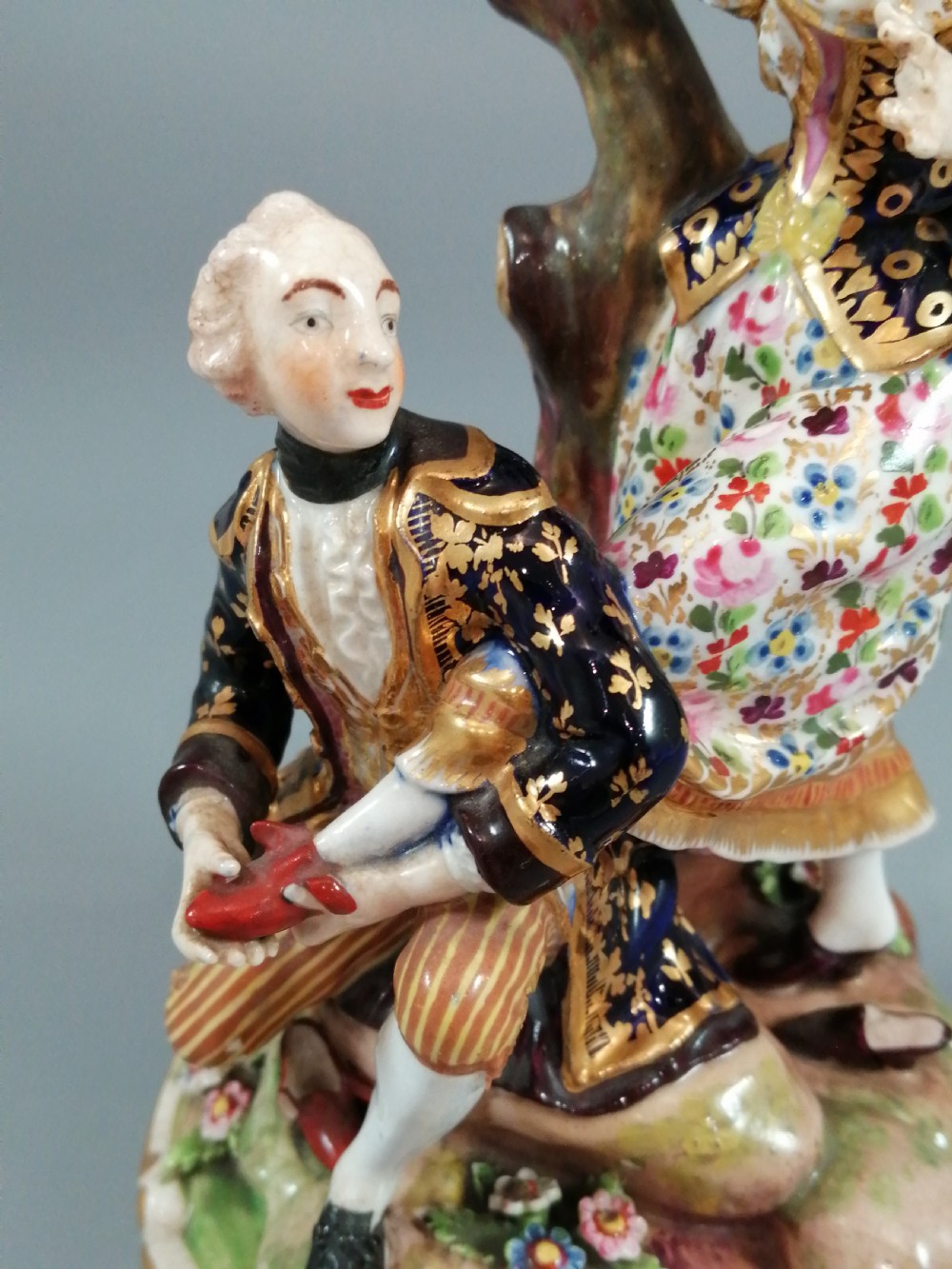 Early 19th-century Derby porcelain figural group depicting a shoemaker and a standing lady beside a tree on a gilded scroll base. View VI