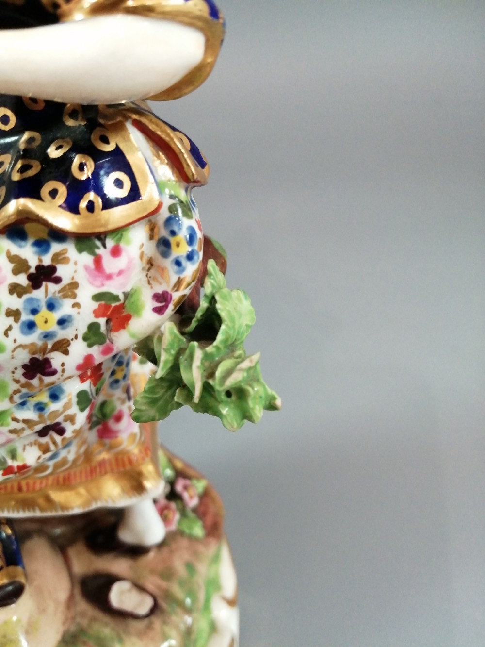 Early 19th-century Derby porcelain figural group depicting a shoemaker and a standing lady beside a tree on a gilded scroll base. View VII