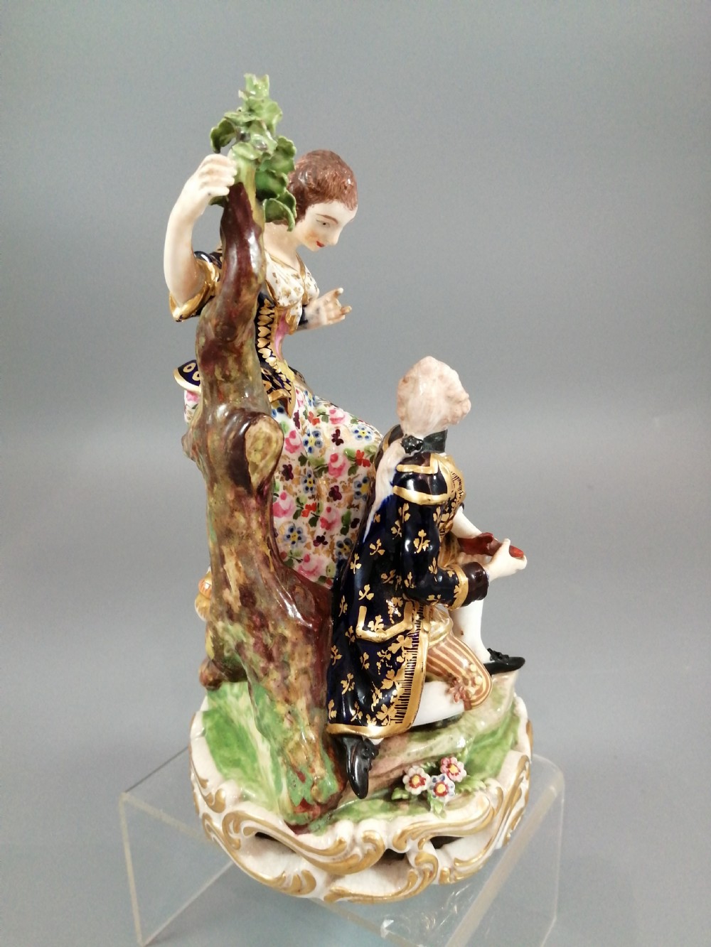 Early 19th-century Derby porcelain figural group depicting a shoemaker and a standing lady beside a tree on a gilded scroll base. View VIII
