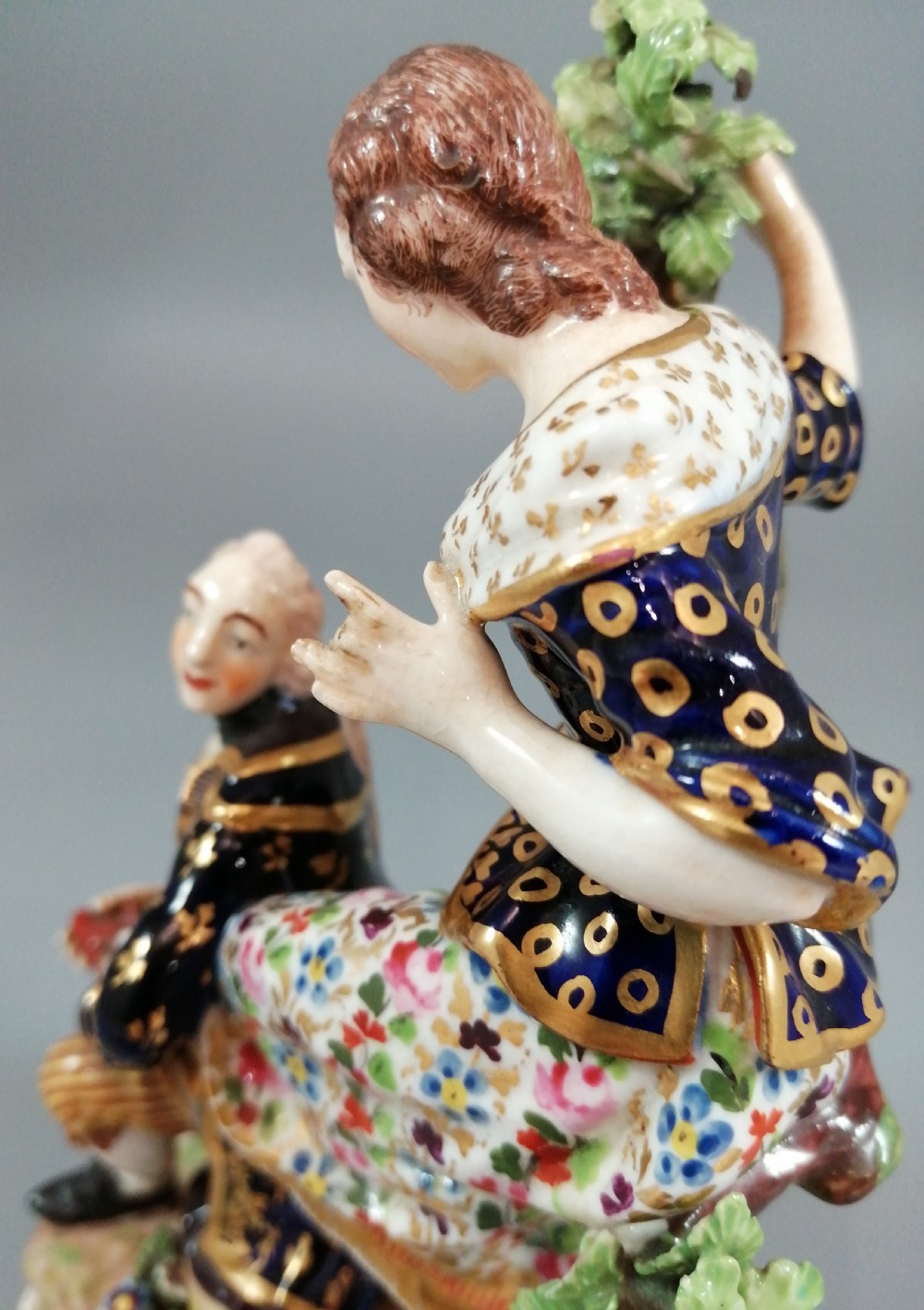 Early 19th-century Derby porcelain figural group depicting a shoemaker and a standing lady beside a tree on a gilded scroll base. View IX