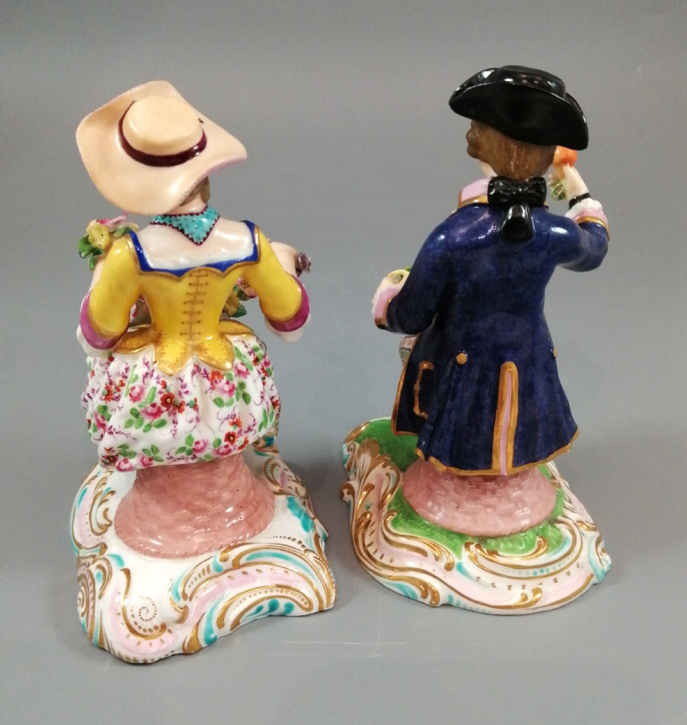 Pair of hand-painted porcelain figurines depicting a male and female gardener seated on Rococo scrolling bases adorned with encrusted flowers. View III
