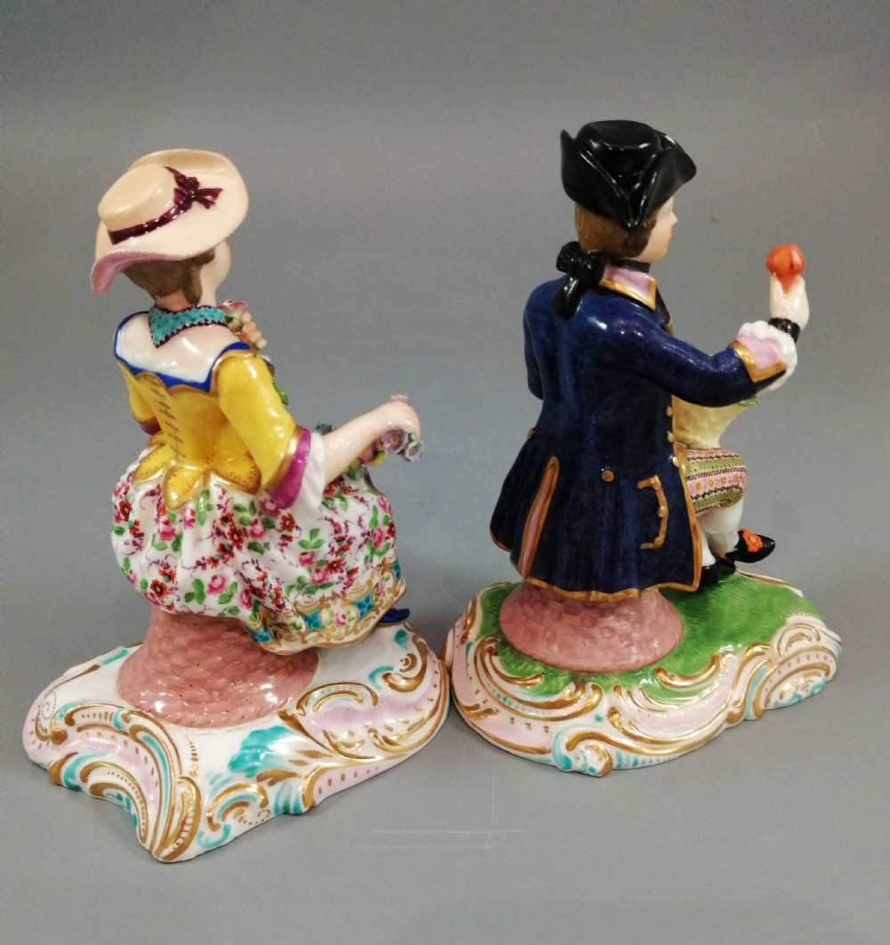 Pair of hand-painted porcelain figurines depicting a male and female gardener seated on Rococo scrolling bases adorned with encrusted flowers. View IV
