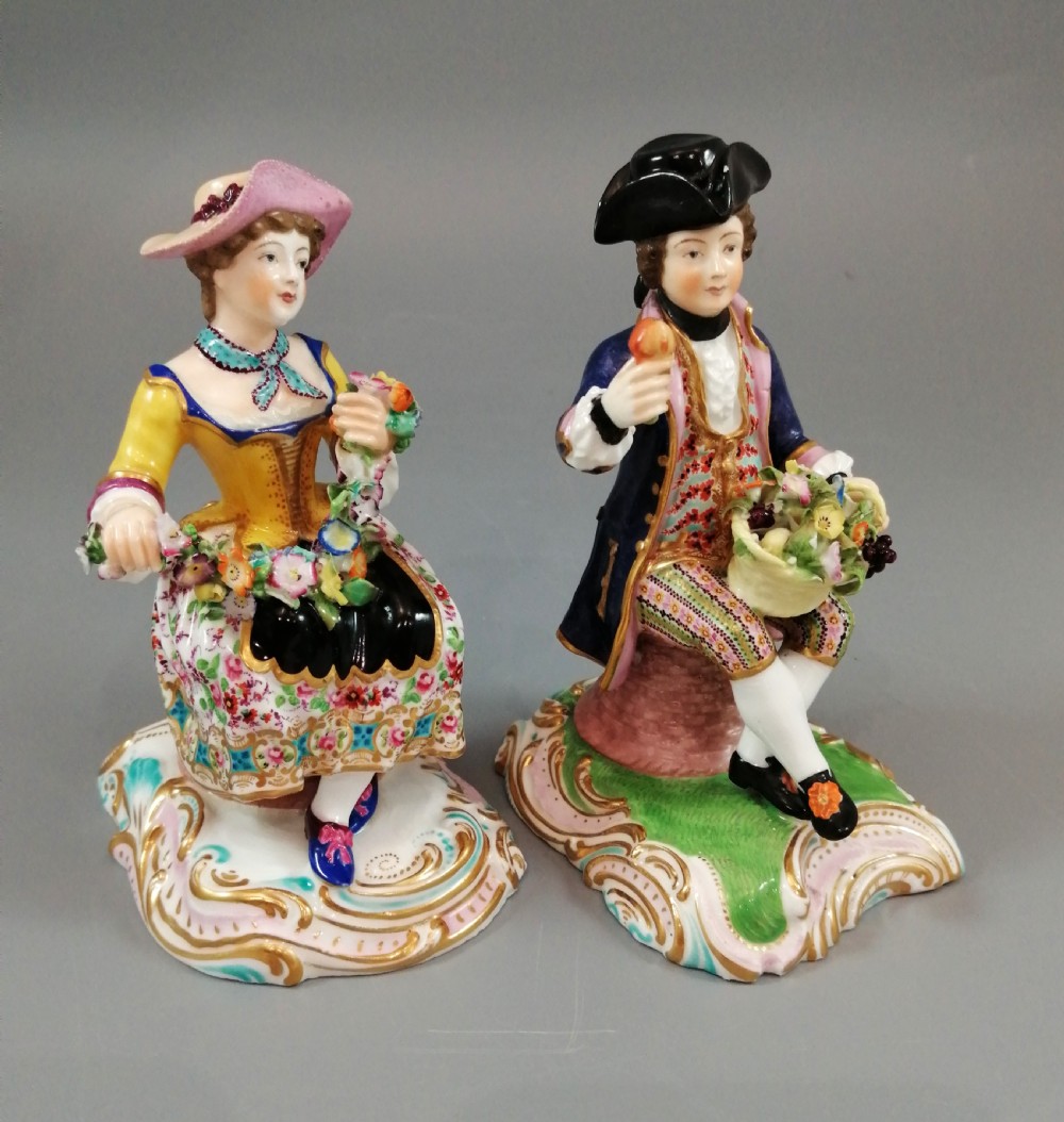 Pair of hand-painted porcelain figurines depicting a male and female gardener seated on Rococo scrolling bases adorned with encrusted flowers. View VI