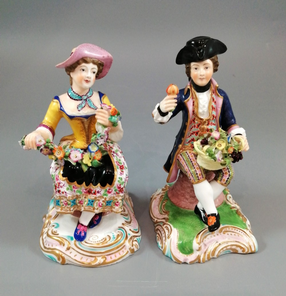 Pair of hand-painted porcelain figurines depicting a male and female gardener seated on Rococo scrolling bases adorned with encrusted flowers. View VII
