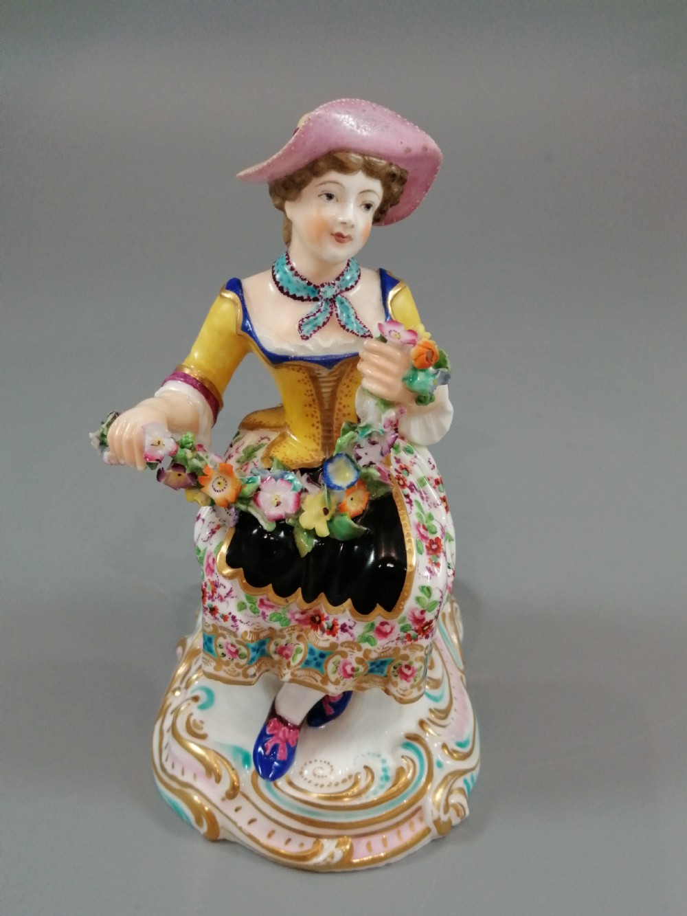 Pair of hand-painted porcelain figurines depicting a male and female gardener seated on Rococo scrolling bases adorned with encrusted flowers. View VIII