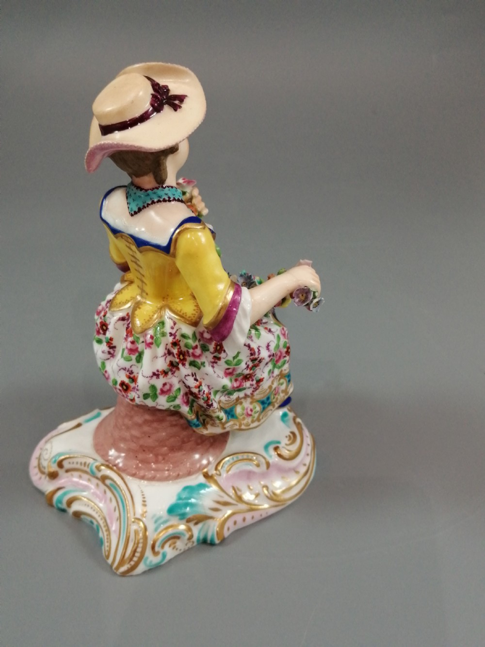 Pair of hand-painted porcelain figurines depicting a male and female gardener seated on Rococo scrolling bases adorned with encrusted flowers. View XI