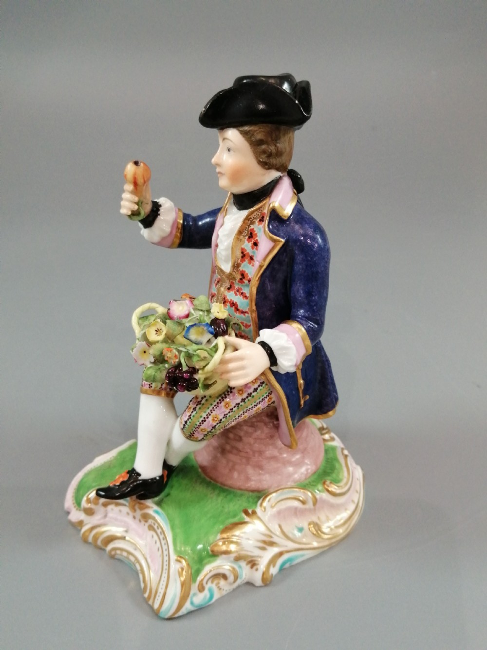Pair of hand-painted porcelain figurines depicting a male and female gardener seated on Rococo scrolling bases adorned with encrusted flowers. View XV