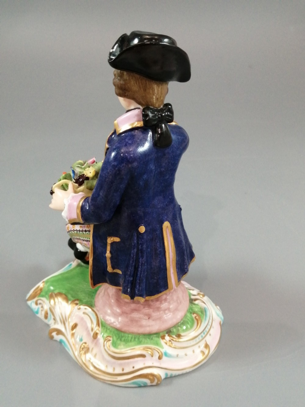Pair of hand-painted porcelain figurines depicting a male and female gardener seated on Rococo scrolling bases adorned with encrusted flowers. View XVI