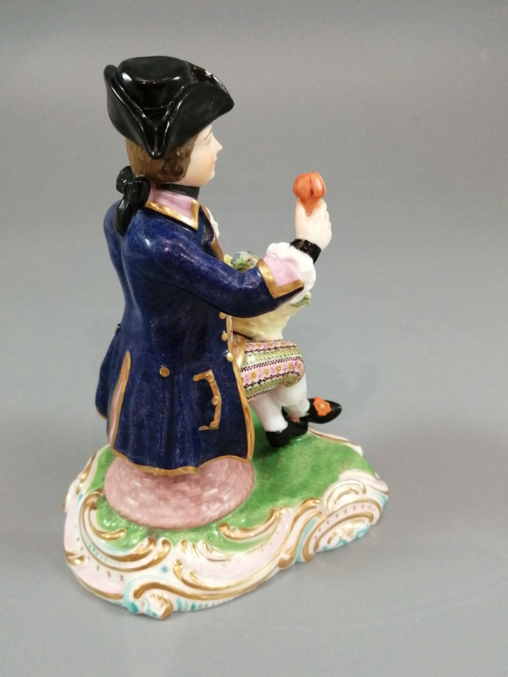 Pair of hand-painted porcelain figurines depicting a male and female gardener seated on Rococo scrolling bases adorned with encrusted flowers. View XVII