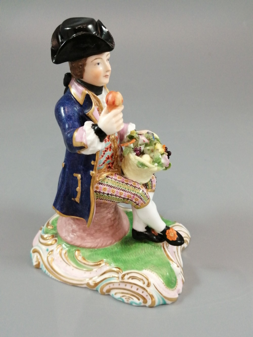 Pair of hand-painted porcelain figurines depicting a male and female gardener seated on Rococo scrolling bases adorned with encrusted flowers. View XVIII