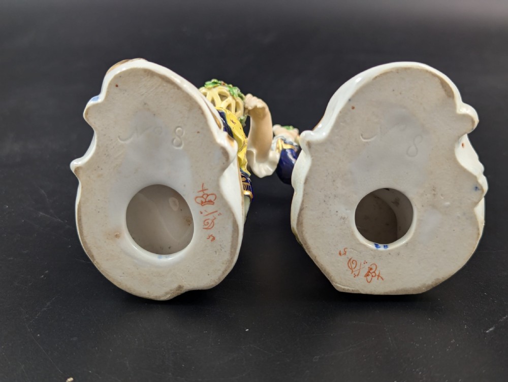 A pair of antique hand-painted Derby porcelain figurines featuring a young female gardener with a basket of flowers and a male gardener holding fruit on gilt scroll bases. View VIII