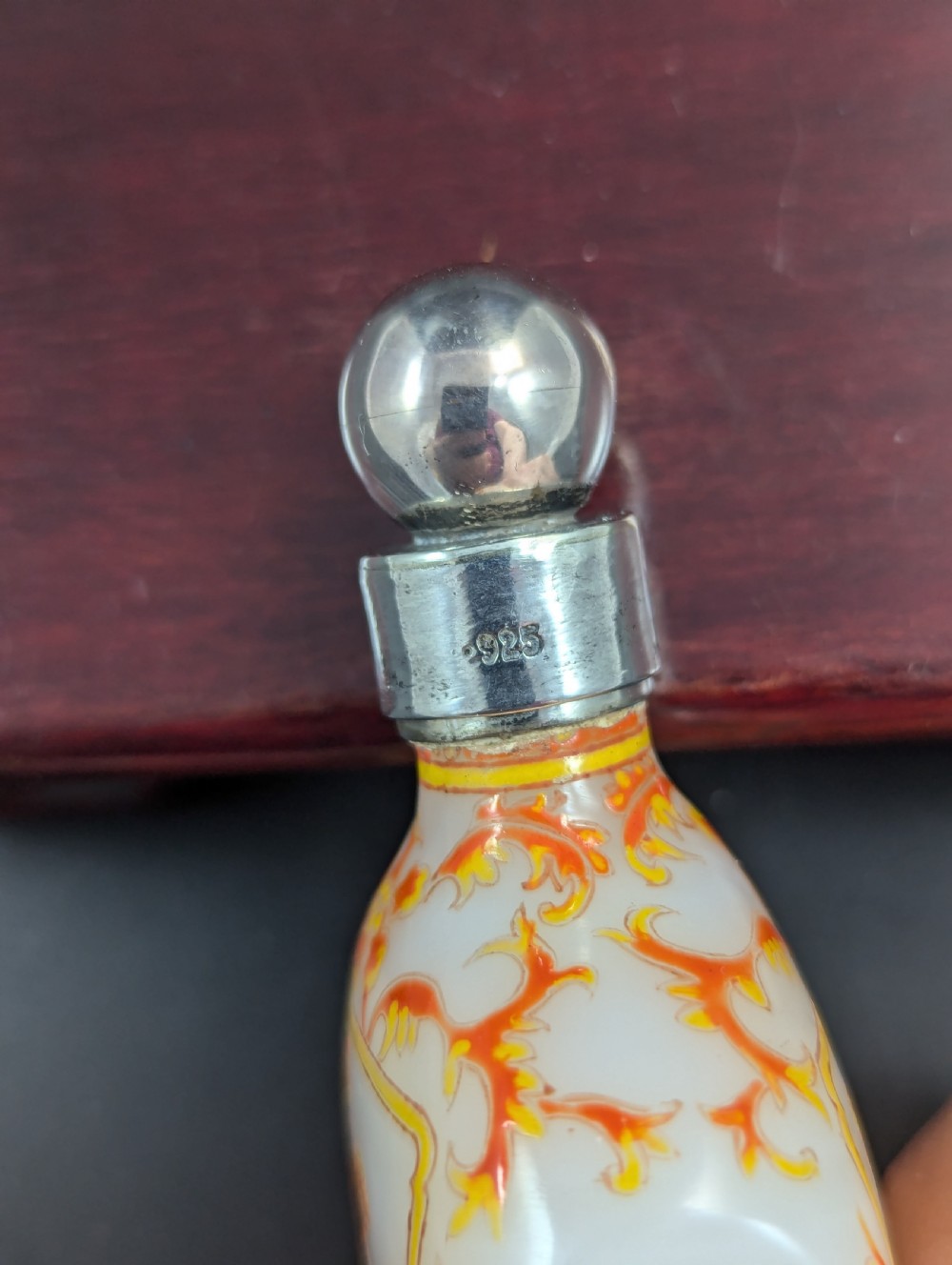 An opaque white glass snuff bottle featuring orange lotus enamel decoration within a central panel and a silver-tone spherical stopper. View VIII