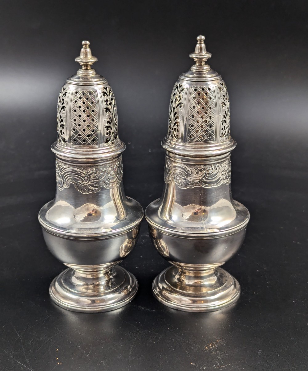 A pair of George II sterling silver baluster-form casters featuring pierced lattice tops, chased scroll detailing, and stepped pedestal bases. View V