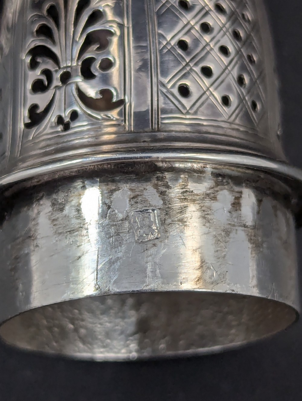 A pair of George II sterling silver baluster-form casters featuring pierced lattice tops, chased scroll detailing, and stepped pedestal bases. View X