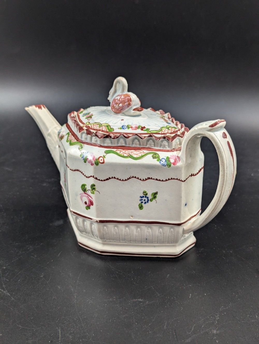 An octagonal off-white antique pearlware teapot decorated with hand-painted floral sprigs, a fluted base, and a swan-form lid knop. View II