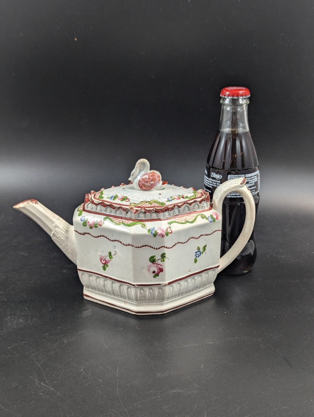 An octagonal off-white antique pearlware teapot decorated with hand-painted floral sprigs, a fluted base, and a swan-form lid knop. View X