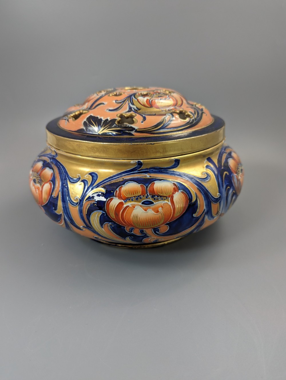 An Edwardian Moorcroft Macintyre ceramic pot pourri jar with a pierced lid, featuring hand-painted tube-lined floral decoration in cobalt blue, coral, and gold. View II