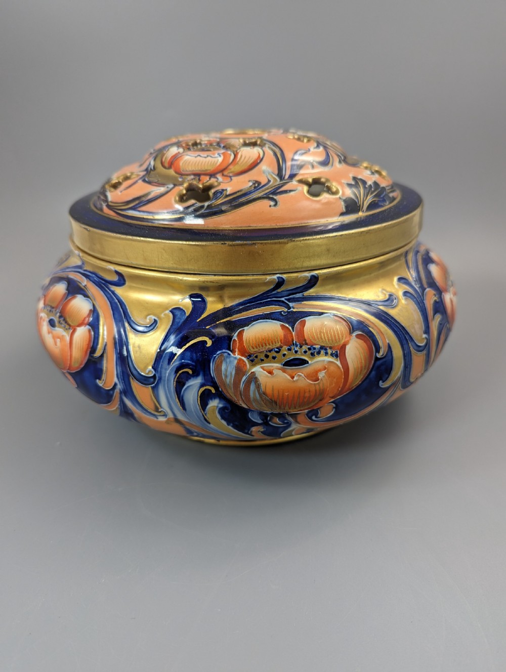 An Edwardian Moorcroft Macintyre ceramic pot pourri jar with a pierced lid, featuring hand-painted tube-lined floral decoration in cobalt blue, coral, and gold. View III