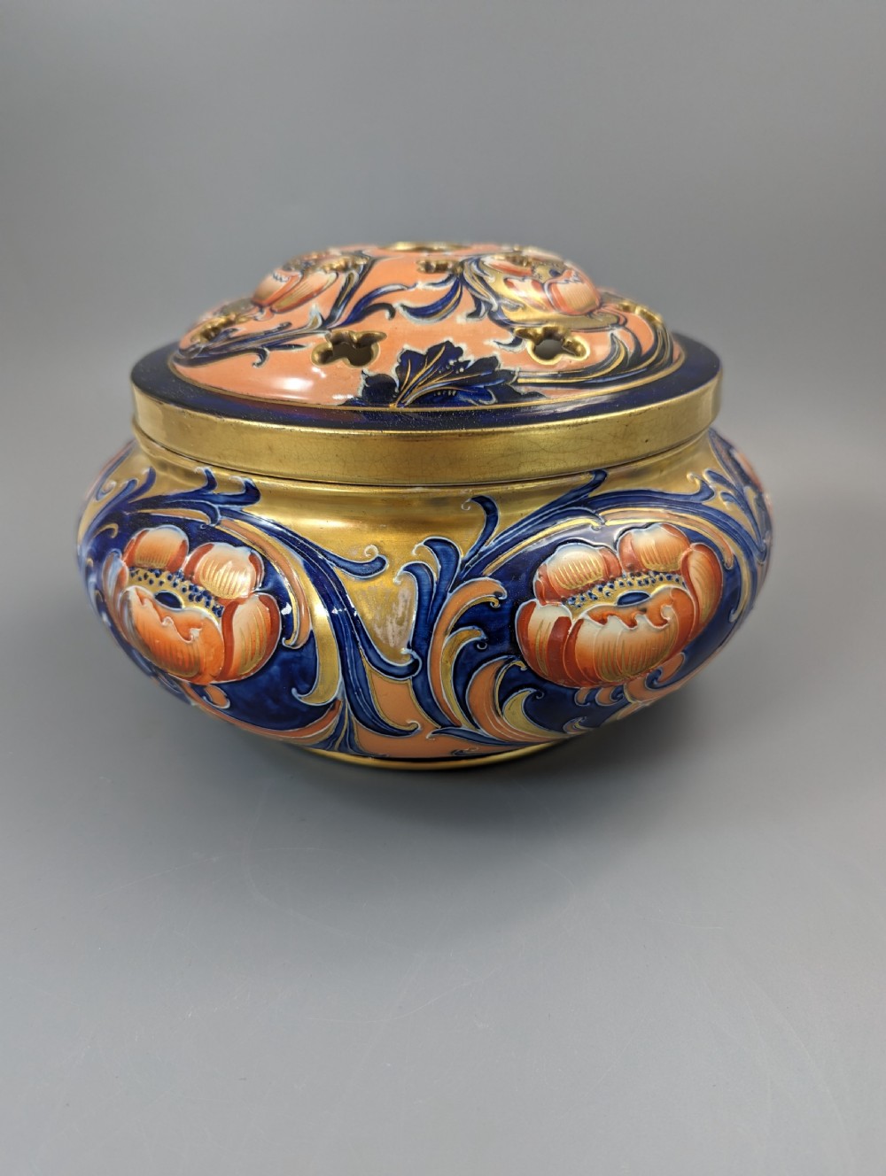 An Edwardian Moorcroft Macintyre ceramic pot pourri jar with a pierced lid, featuring hand-painted tube-lined floral decoration in cobalt blue, coral, and gold. View IV