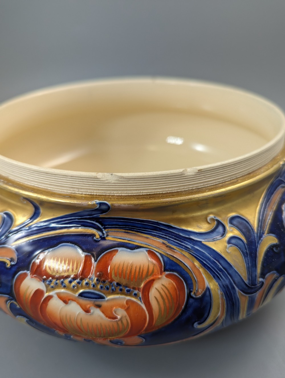 An Edwardian Moorcroft Macintyre ceramic pot pourri jar with a pierced lid, featuring hand-painted tube-lined floral decoration in cobalt blue, coral, and gold. View VI