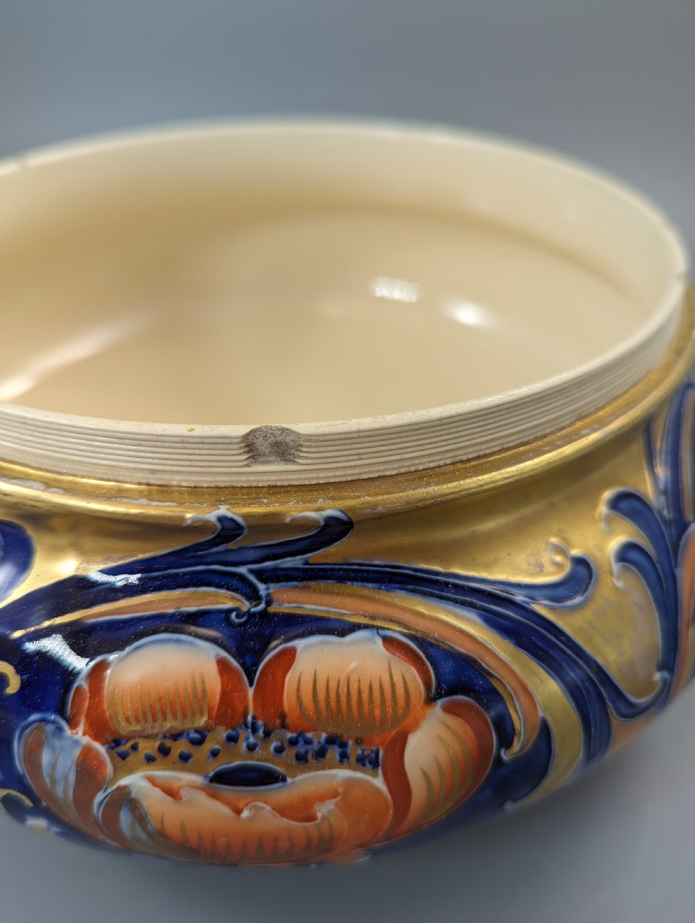 An Edwardian Moorcroft Macintyre ceramic pot pourri jar with a pierced lid, featuring hand-painted tube-lined floral decoration in cobalt blue, coral, and gold. View VIII