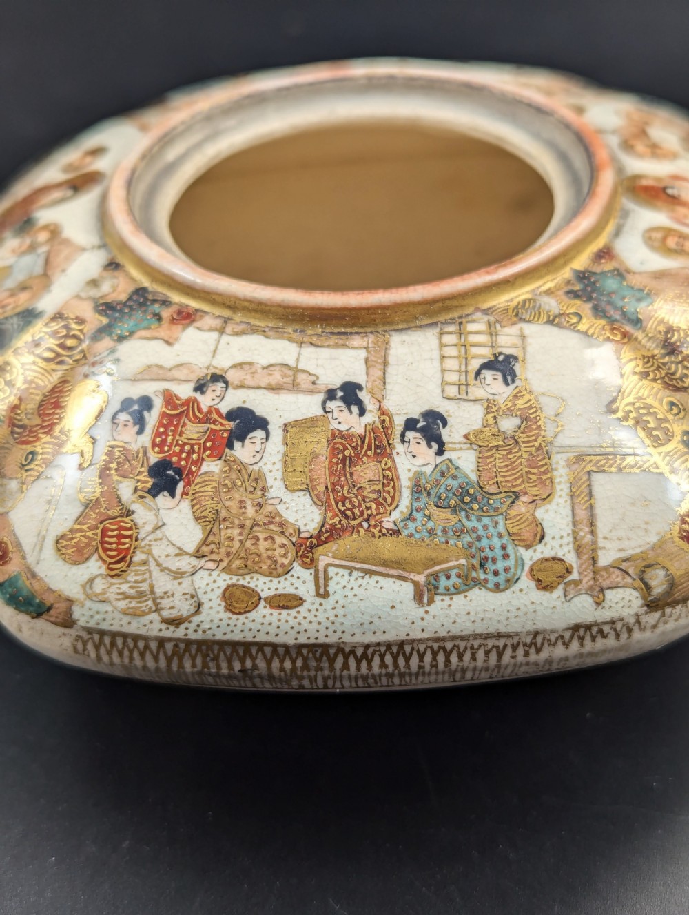 A squarish, lobed Satsuma earthenware vessel featuring hand-painted figures with gold halos, elaborate gilded borders, and a crackled ivory glaze. View III