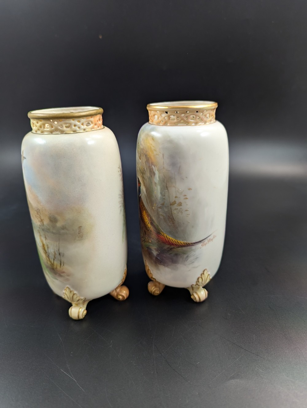 A pair of Edwardian Royal Worcester porcelain vases featuring hand-painted pheasants in natural landscapes, with reticulated rims and gilt scroll feet. View II