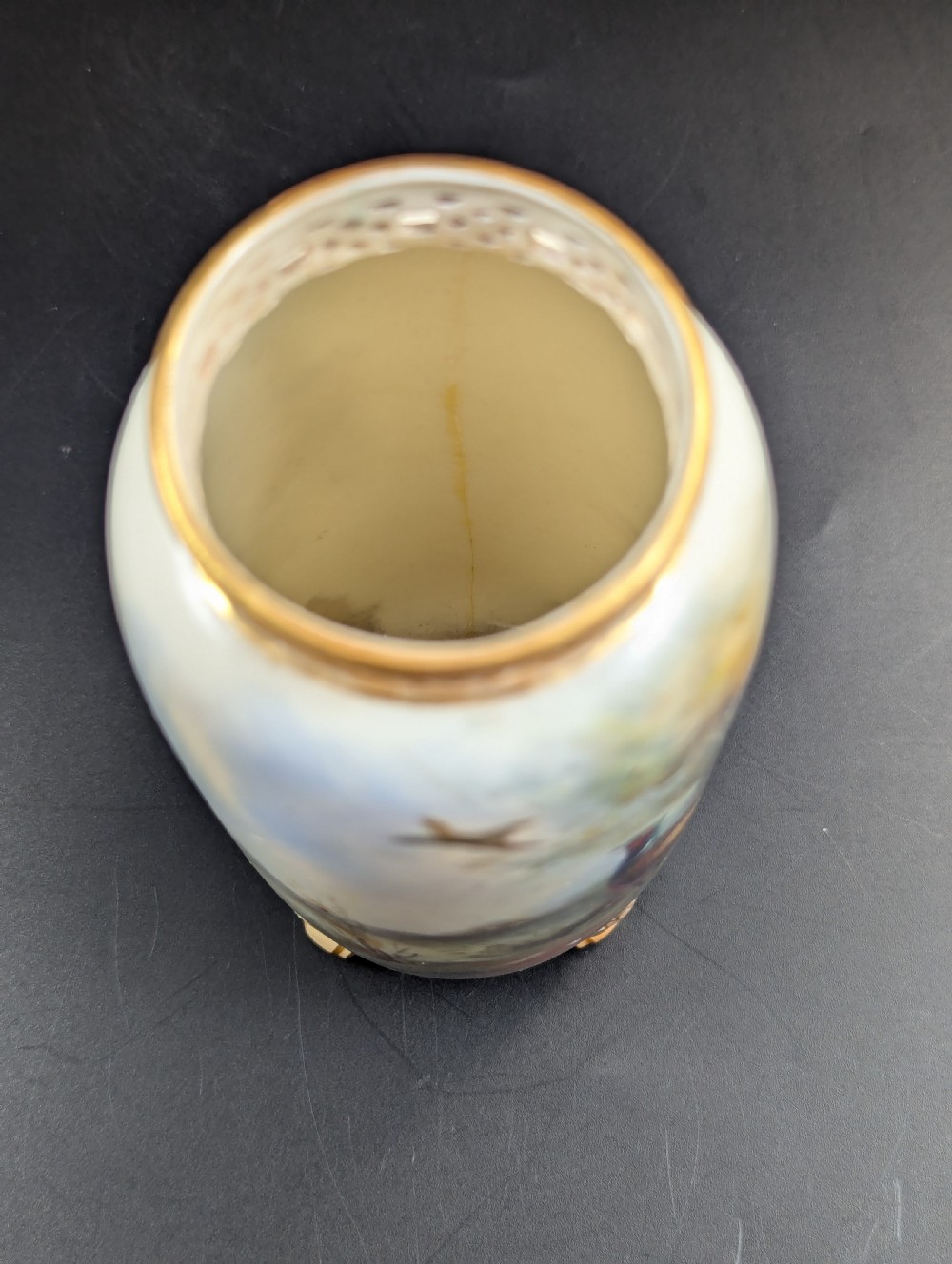 A pair of Edwardian Royal Worcester porcelain vases featuring hand-painted pheasants in natural landscapes, with reticulated rims and gilt scroll feet. View X
