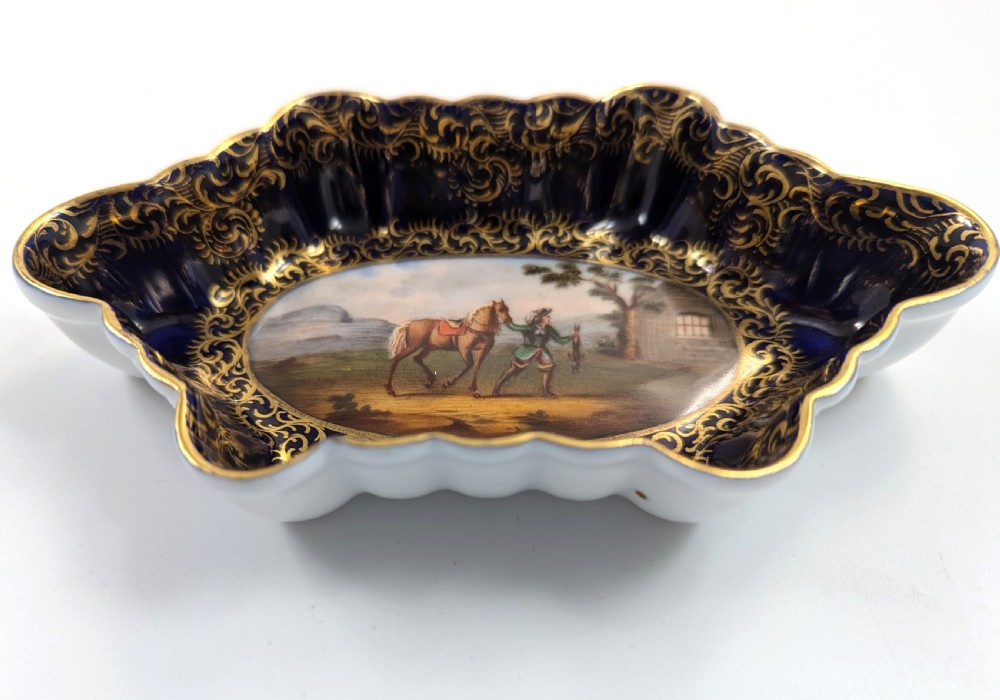 An oval lobed Dresden porcelain dish featuring a cobalt blue rim decorated with gilt scrollwork and a central hand-painted equestrian scene. View II