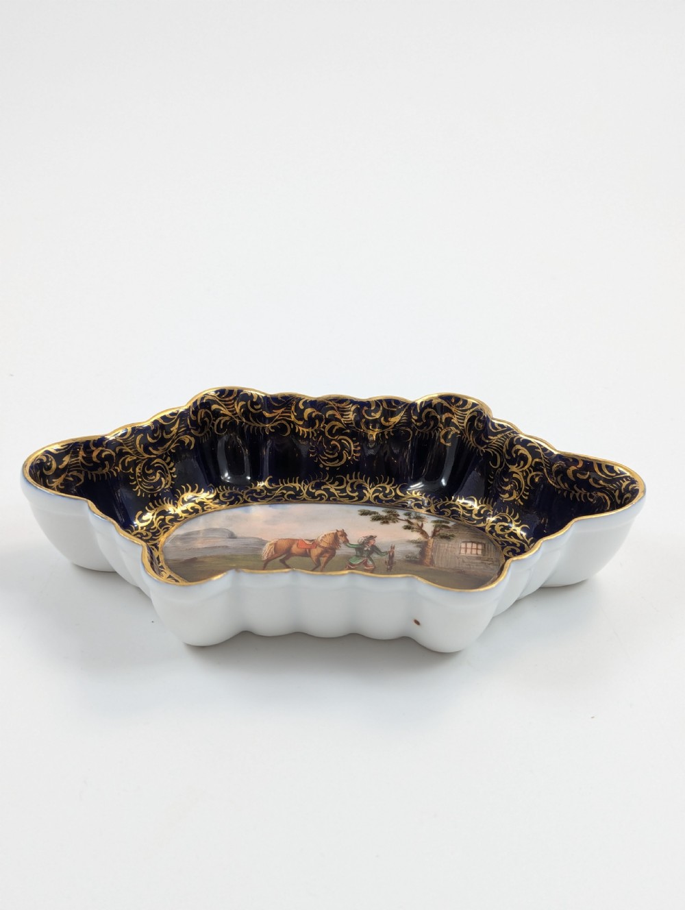An oval lobed Dresden porcelain dish featuring a cobalt blue rim decorated with gilt scrollwork and a central hand-painted equestrian scene. View III