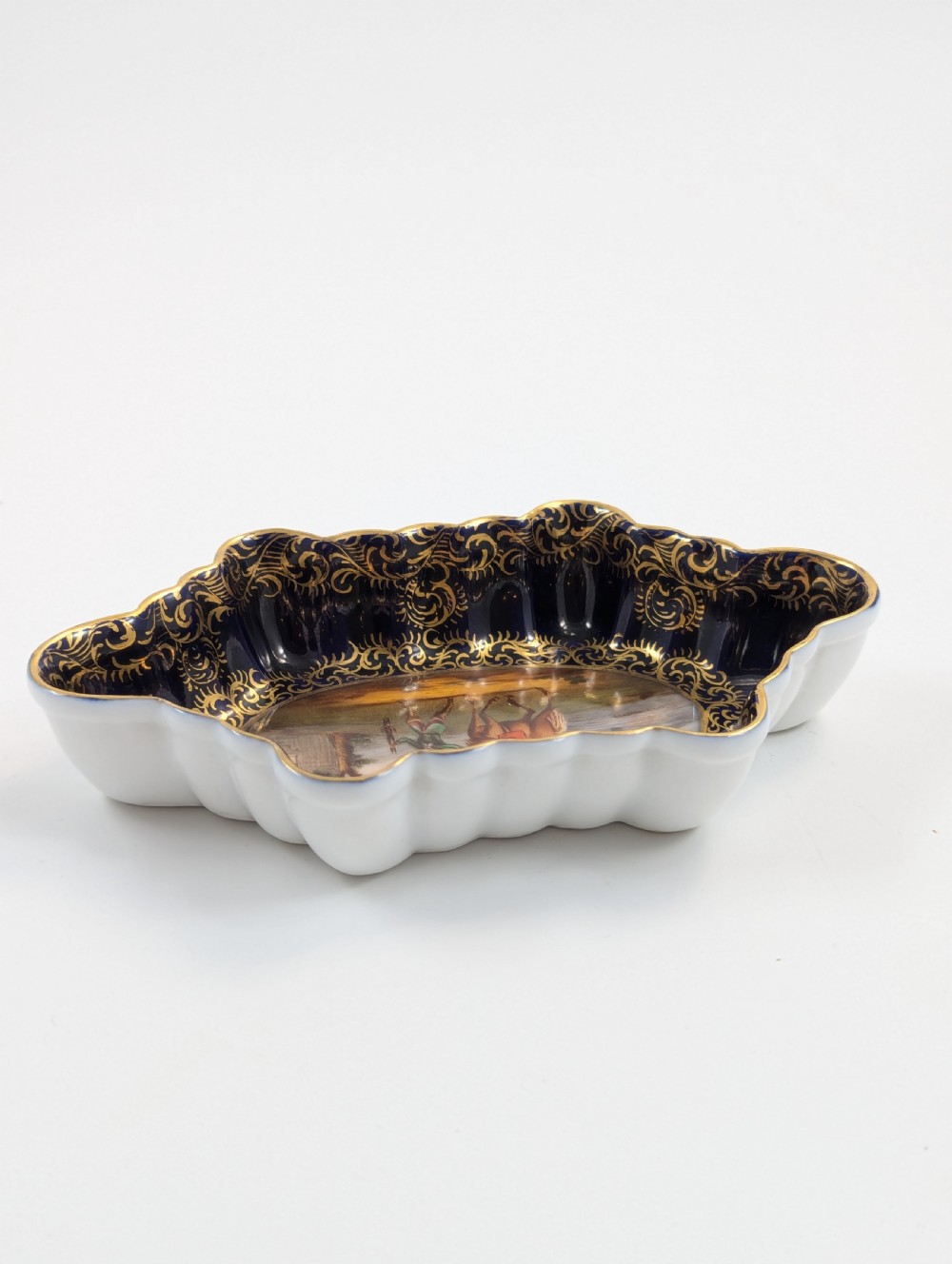 An oval lobed Dresden porcelain dish featuring a cobalt blue rim decorated with gilt scrollwork and a central hand-painted equestrian scene. View V