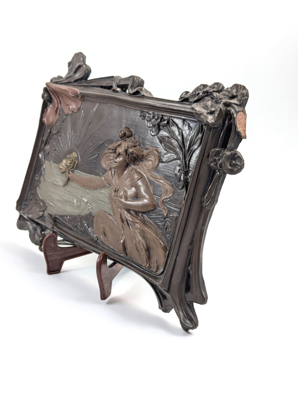 A rectangular French Art Nouveau terracotta relief featuring a draped female figure holding a rose against a rising sun background with a metallic finish. View IV