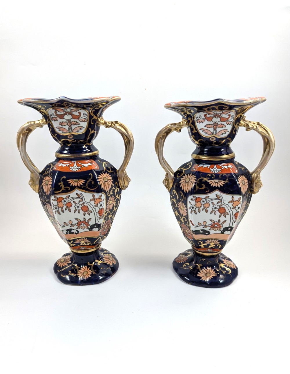 A pair of antique Masons ironstone vases decorated in a cobalt blue and terracotta Imari pattern with double gilt handles.
