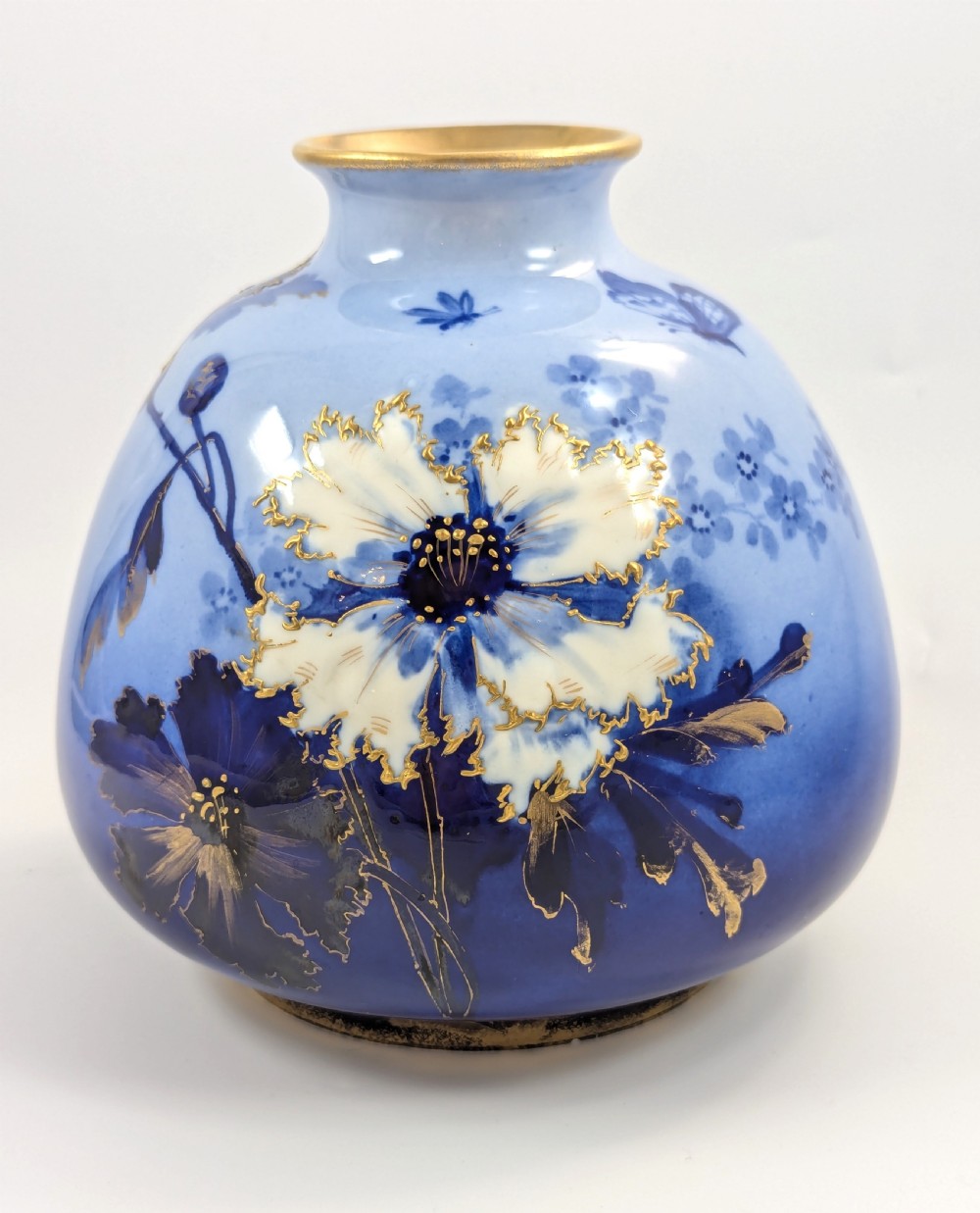 A bulbous Art Nouveau porcelain vase featuring a blue gradient backdrop decorated with hand-painted white chrysanthemums and gold gilt highlights.