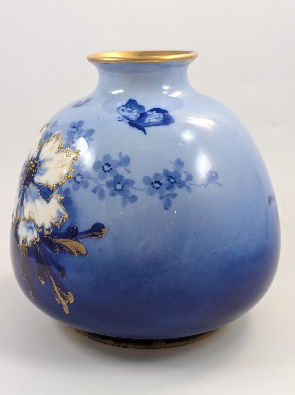 A bulbous Art Nouveau porcelain vase featuring a blue gradient backdrop decorated with hand-painted white chrysanthemums and gold gilt highlights. View II