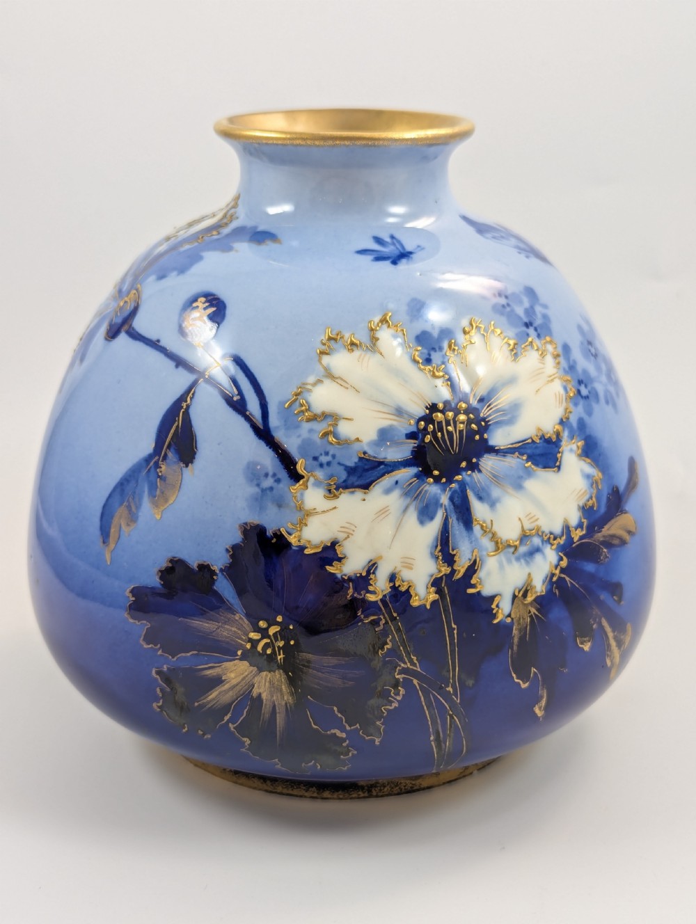 A bulbous Art Nouveau porcelain vase featuring a blue gradient backdrop decorated with hand-painted white chrysanthemums and gold gilt highlights. View X