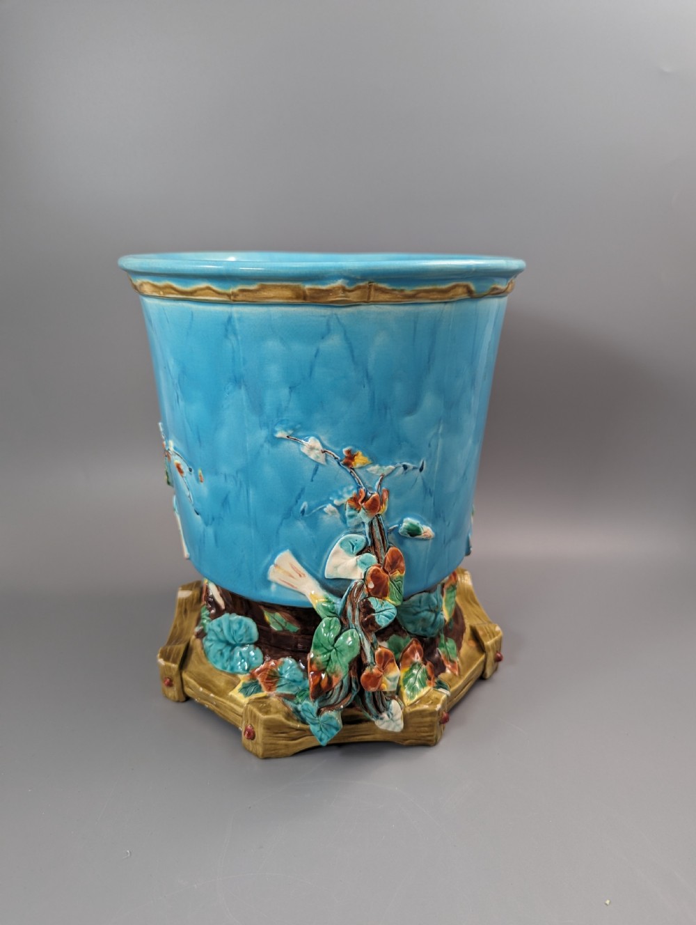 A Victorian Royal Worcester turquoise majolica jardiniere planter featuring relief-moulded foliage and a faux-woodland base.
