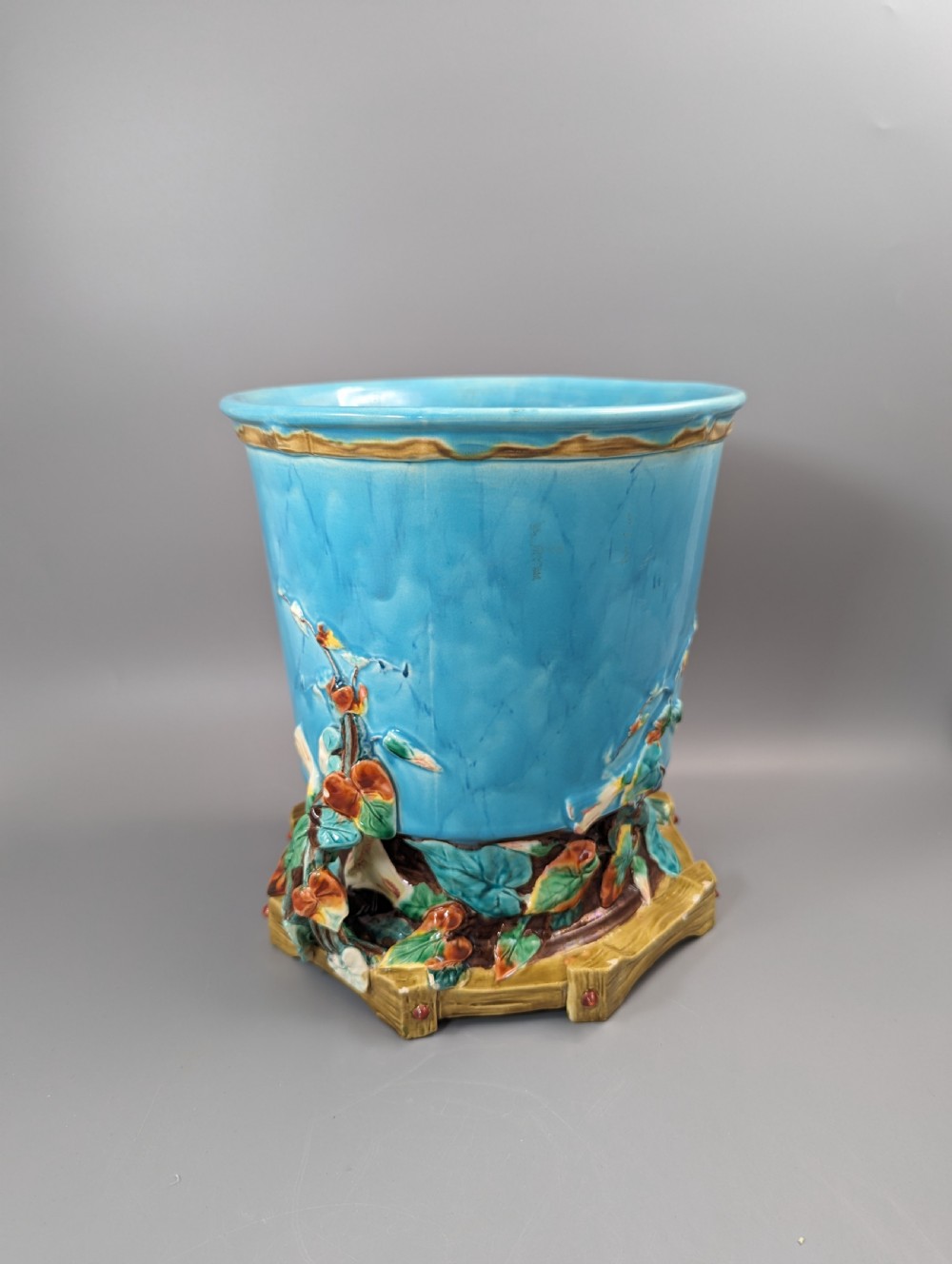 A Victorian Royal Worcester turquoise majolica jardiniere planter featuring relief-moulded foliage and a faux-woodland base. View II