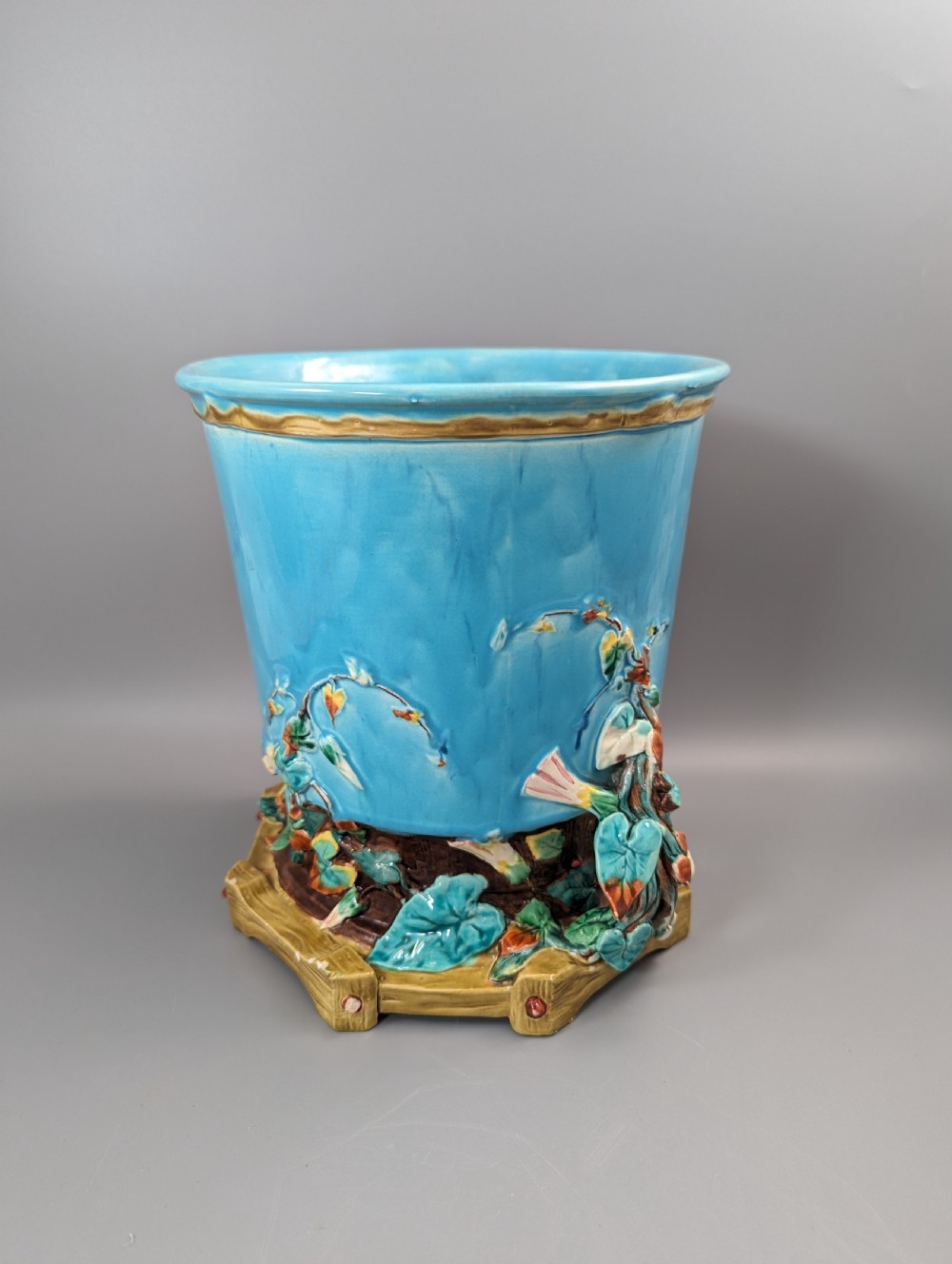 A Victorian Royal Worcester turquoise majolica jardiniere planter featuring relief-moulded foliage and a faux-woodland base. View IV
