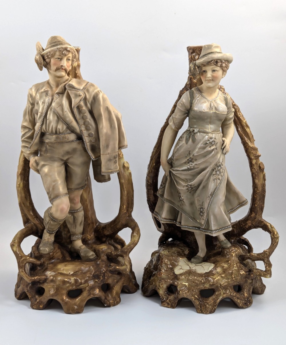 A pair of nineteenth-century Bohemian porcelain figurines depicting a man and woman in folk attire framed by gilded root-like arbours on sculpted bases.
