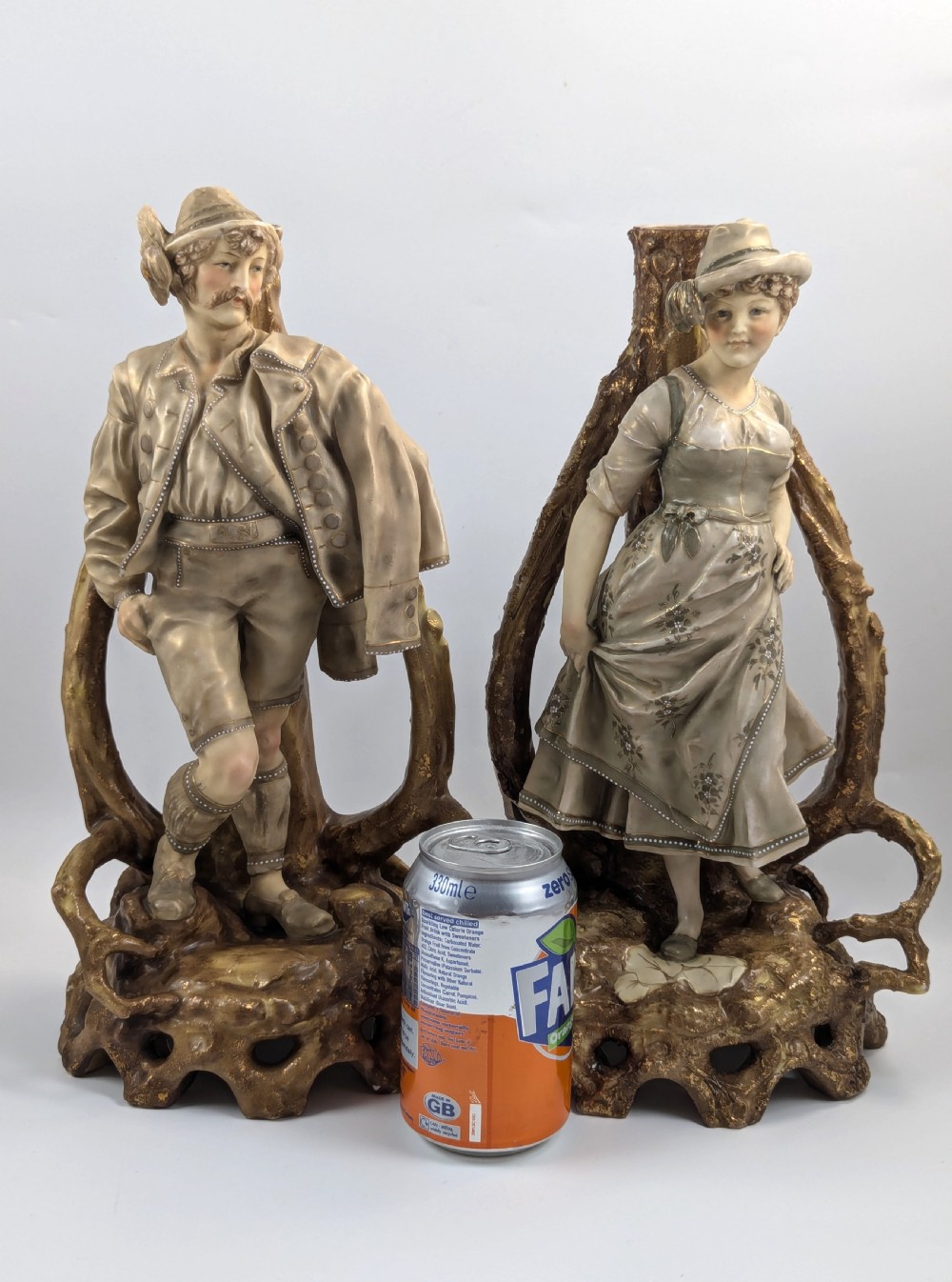 A pair of nineteenth-century Bohemian porcelain figurines depicting a man and woman in folk attire framed by gilded root-like arbours on sculpted bases. View X